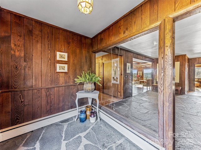 interior space with a baseboard radiator, a wealth of natural light, and wood walls