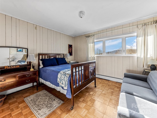 bedroom with light parquet flooring, wooden walls, and a baseboard radiator