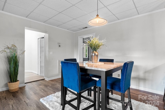 dining area featuring a paneled ceiling, crown molding, and hardwood / wood-style flooring