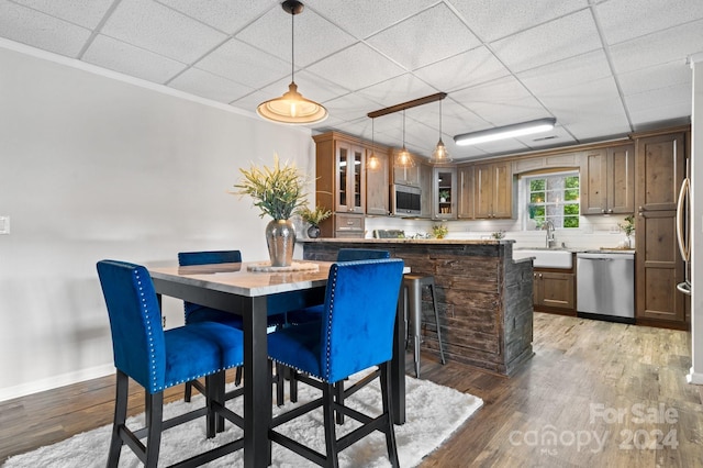 dining area featuring sink, a drop ceiling, and light hardwood / wood-style floors