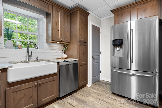 kitchen with light hardwood / wood-style flooring, appliances with stainless steel finishes, light stone countertops, a paneled ceiling, and sink