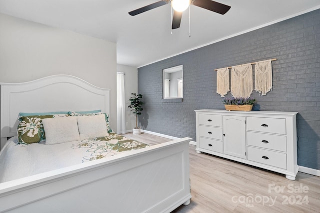 bedroom featuring ceiling fan, brick wall, and light hardwood / wood-style floors