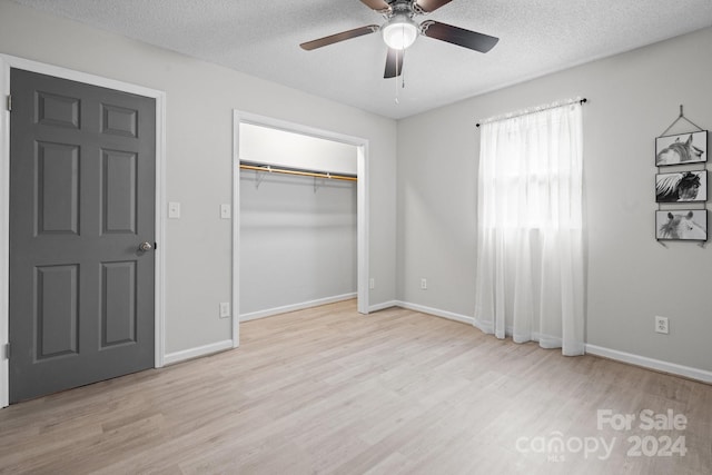 unfurnished bedroom featuring ceiling fan, light wood-type flooring, a textured ceiling, and a closet