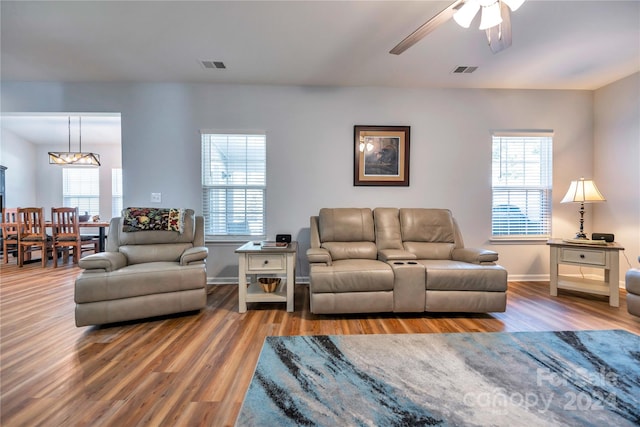 living room with a wealth of natural light, ceiling fan with notable chandelier, and dark hardwood / wood-style floors