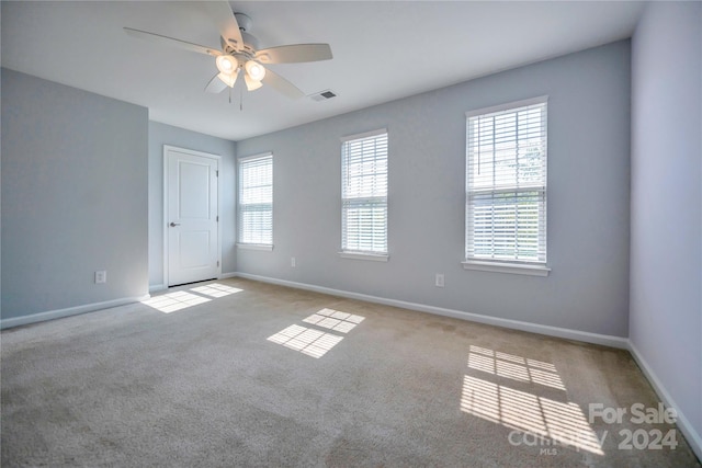 carpeted empty room with ceiling fan and a healthy amount of sunlight