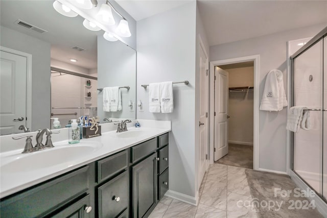 bathroom with double vanity, a shower with door, and tile patterned floors