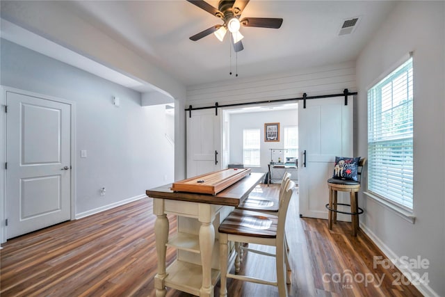 dining room with ceiling fan, dark hardwood / wood-style floors, and a barn door