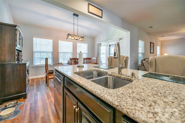 kitchen with sink, dark wood-type flooring, light stone countertops, dishwasher, and pendant lighting