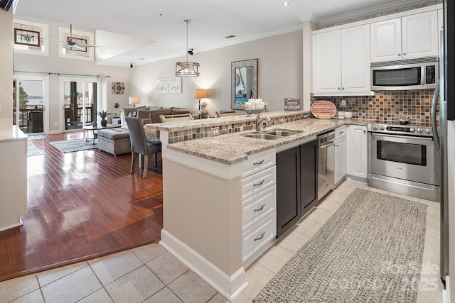 kitchen featuring sink, light stone counters, kitchen peninsula, white cabinets, and appliances with stainless steel finishes