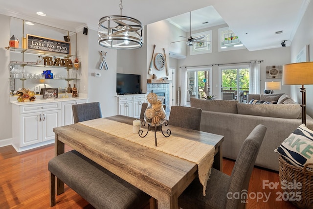 dining area with ceiling fan with notable chandelier, crown molding, and dark wood-type flooring