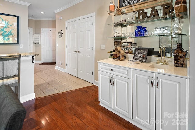 bar with white cabinets, tile patterned flooring, ornamental molding, and sink