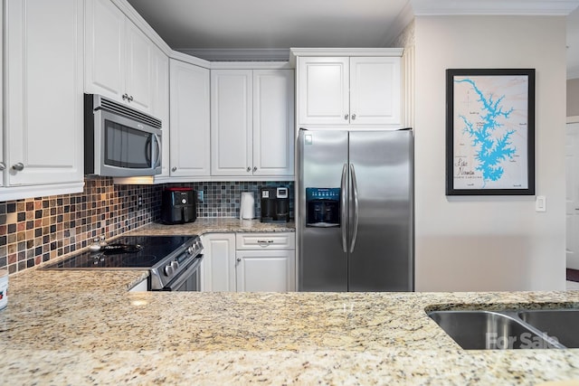 kitchen with light stone countertops, white cabinetry, backsplash, and appliances with stainless steel finishes