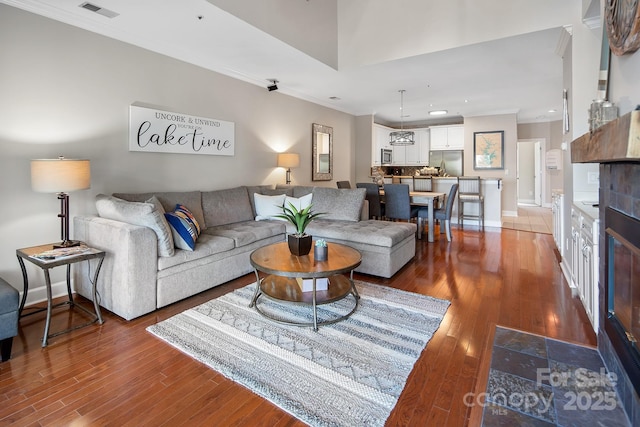 living room featuring dark hardwood / wood-style flooring, a fireplace, and ornamental molding