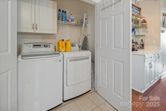 clothes washing area with cabinets, washer and clothes dryer, and light tile patterned flooring