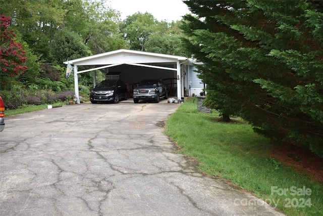 view of parking / parking lot with a carport and a yard