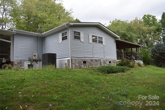 view of side of home with central AC and a lawn