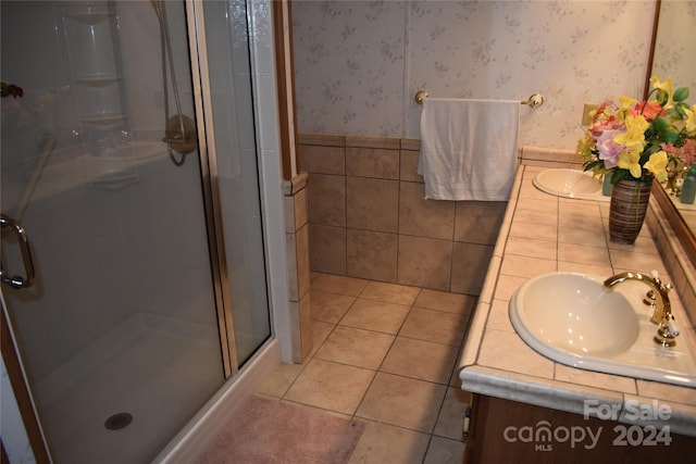 bathroom with tile patterned flooring, vanity, tile walls, and a shower with shower door