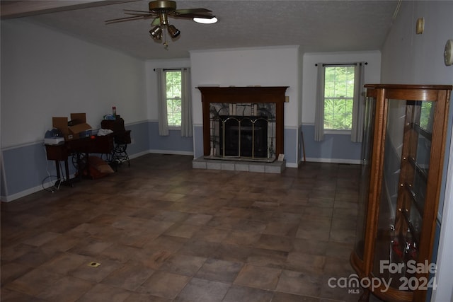 living room with a textured ceiling, a tile fireplace, and a healthy amount of sunlight