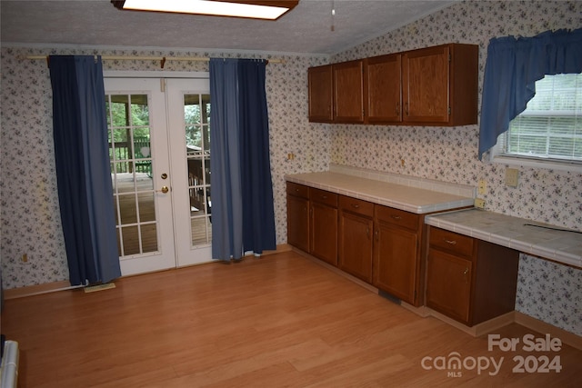 kitchen with french doors, a textured ceiling, light hardwood / wood-style flooring, and a wealth of natural light