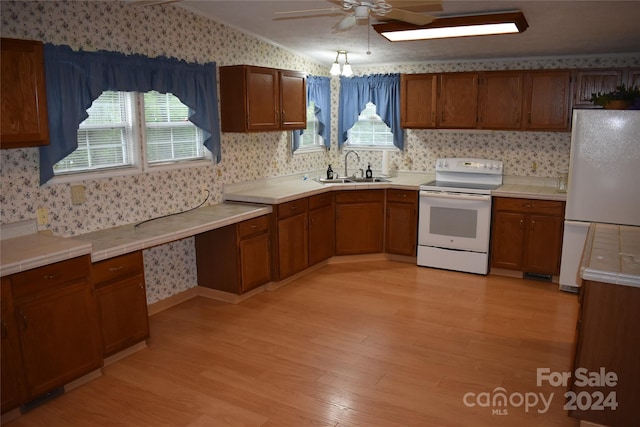 kitchen featuring lofted ceiling, sink, white appliances, and light hardwood / wood-style flooring