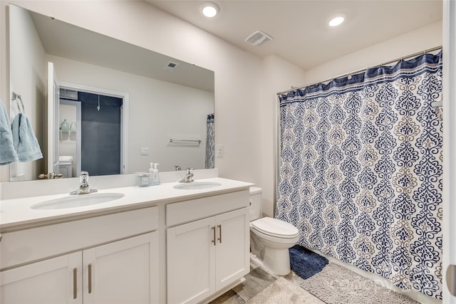 bathroom featuring tile patterned floors, double vanity, and toilet