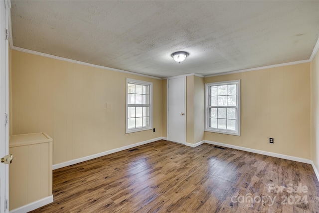 empty room featuring a textured ceiling, hardwood / wood-style floors, and crown molding