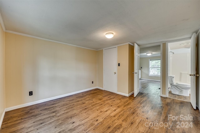 unfurnished bedroom with ensuite bath, crown molding, and hardwood / wood-style floors