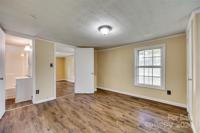 unfurnished room with a textured ceiling, crown molding, and hardwood / wood-style flooring