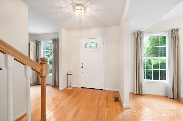 foyer featuring light wood-type flooring and a textured ceiling