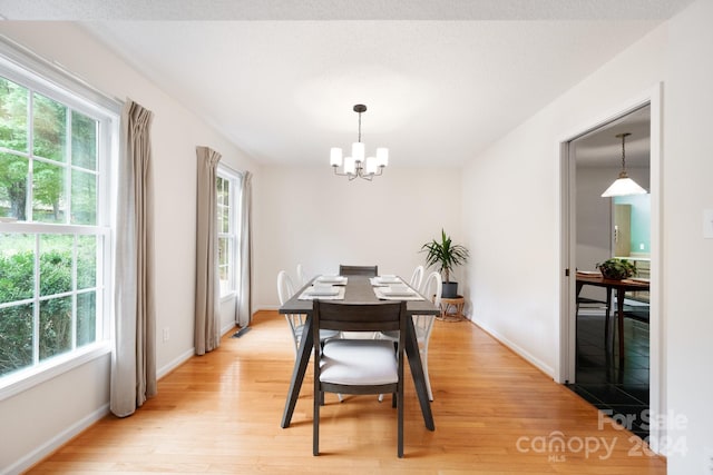 dining space featuring light wood-type flooring, plenty of natural light, and an inviting chandelier