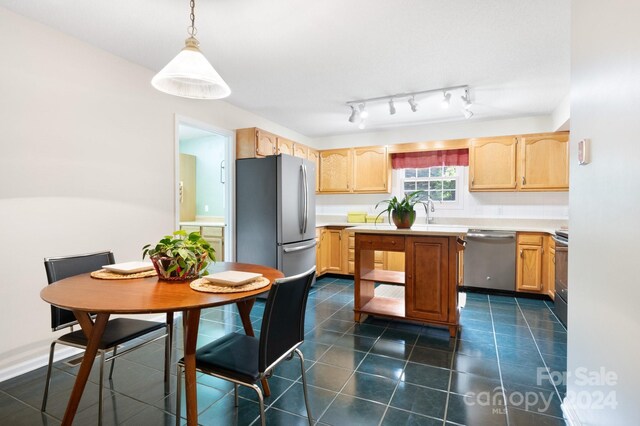 kitchen featuring light brown cabinets, rail lighting, appliances with stainless steel finishes, dark tile patterned floors, and decorative light fixtures