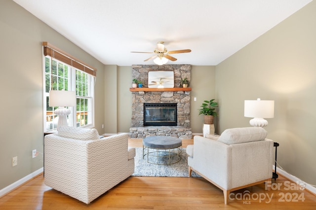 living room with ceiling fan, light wood-type flooring, and a fireplace