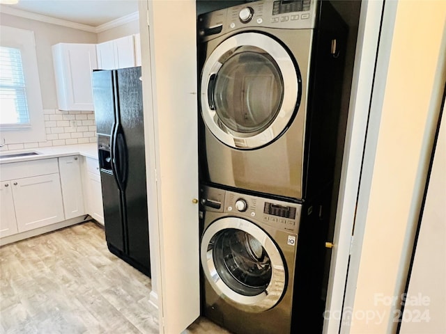 laundry room with stacked washer and dryer, crown molding, and light wood-type flooring