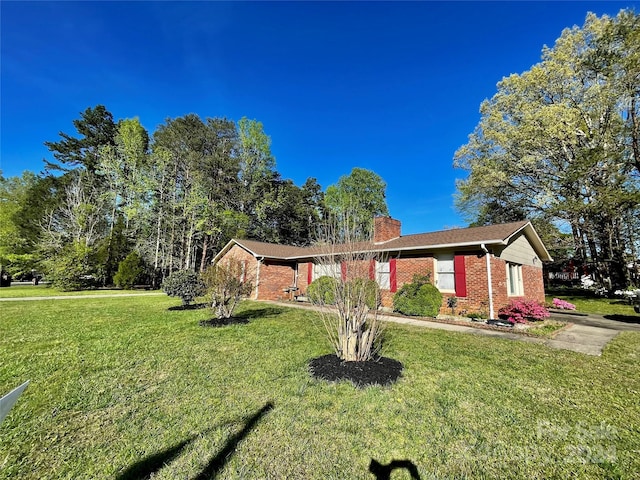 ranch-style home with a front yard, a chimney, and brick siding