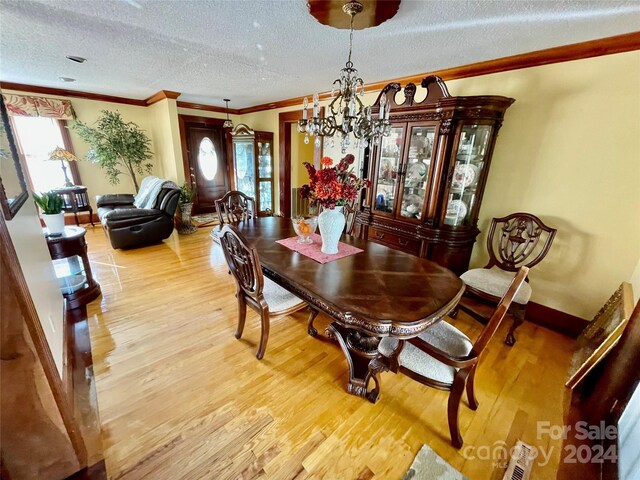 dining room featuring visible vents, crown molding, a textured ceiling, and wood finished floors