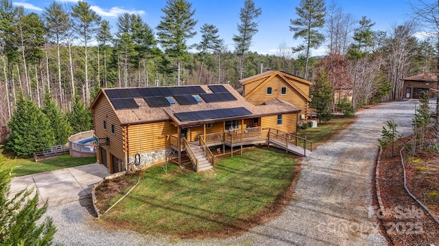 log cabin featuring solar panels, a front lawn, a garage, and a wooden deck