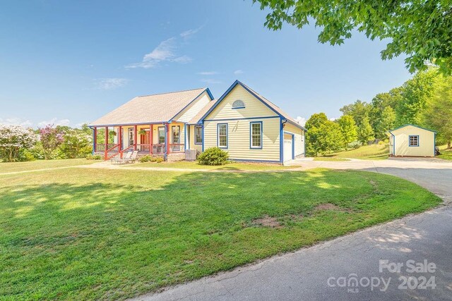 view of front of house with an outbuilding, a porch, cooling unit, a front lawn, and a garage