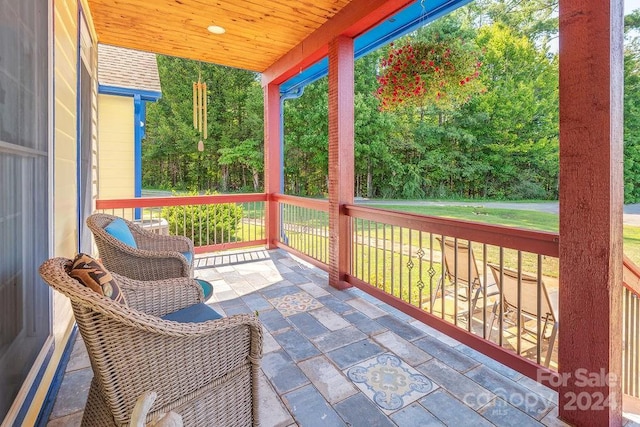 wooden terrace with a lawn and covered porch