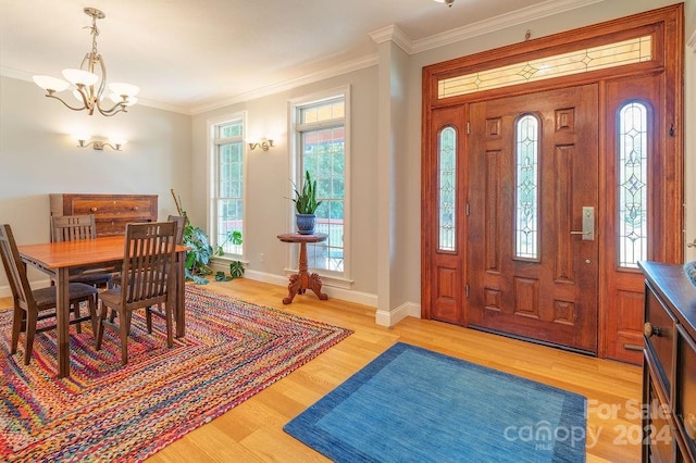 entrance foyer featuring ornamental molding, a chandelier, and light hardwood / wood-style floors