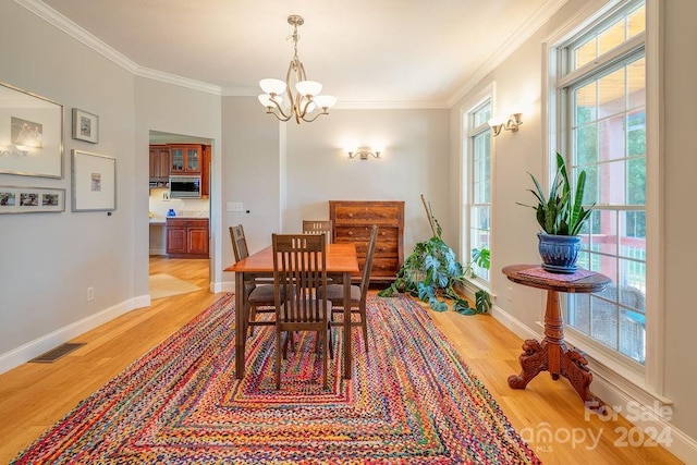 dining room with ornamental molding, a chandelier, and light wood-type flooring