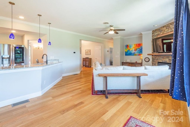 dining room with sink, crown molding, hardwood / wood-style flooring, ceiling fan, and a fireplace