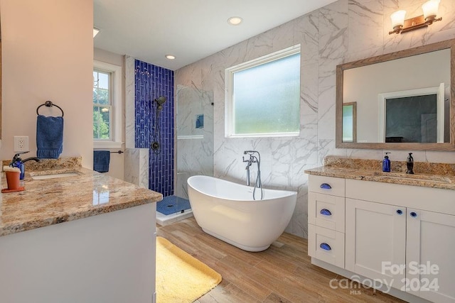 bathroom with wood-type flooring, plus walk in shower, vanity, and tile walls