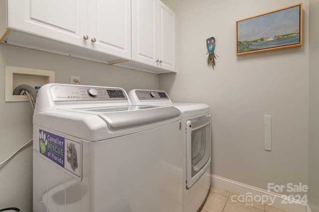 laundry area featuring cabinets, washing machine and dryer, and light tile patterned floors