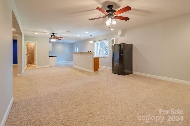 unfurnished living room featuring light colored carpet and ceiling fan