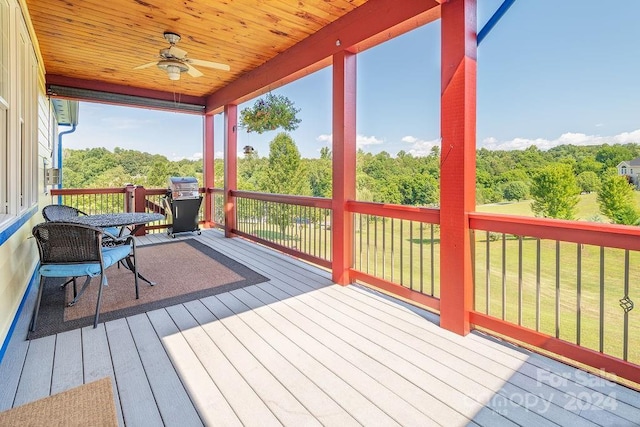 wooden terrace with a grill, a lawn, and ceiling fan