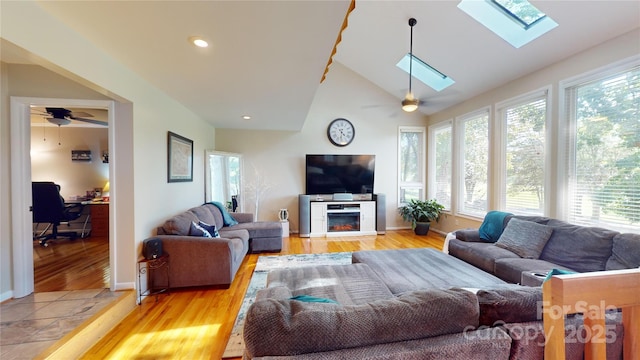 living room with ceiling fan, light wood-type flooring, and lofted ceiling