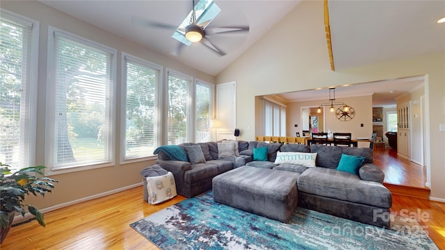 living room with vaulted ceiling, light hardwood / wood-style floors, and ceiling fan with notable chandelier