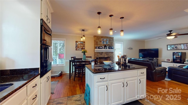 kitchen with pendant lighting, white cabinets, a fireplace, ceiling fan, and crown molding