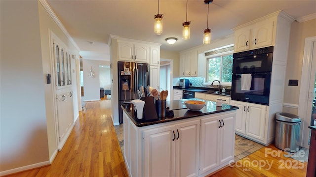 kitchen with white cabinetry, black appliances, hanging light fixtures, and sink