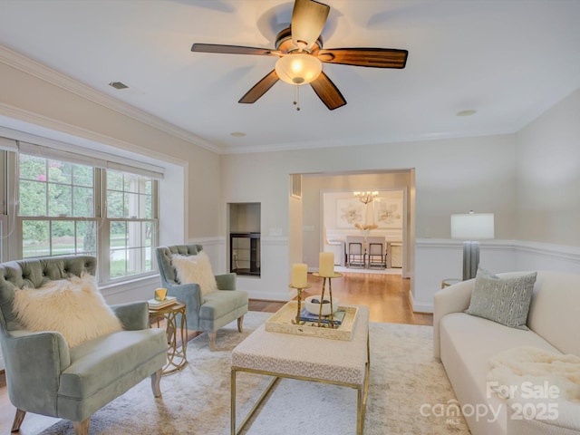 living room featuring ceiling fan with notable chandelier, light hardwood / wood-style floors, and crown molding